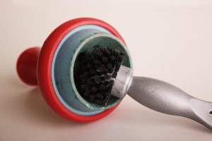 Ein roter Silikonkopf mit Einsatz aus Schamotte wird mit einer SAUBA Bürste für Tabakköpfe geputzt