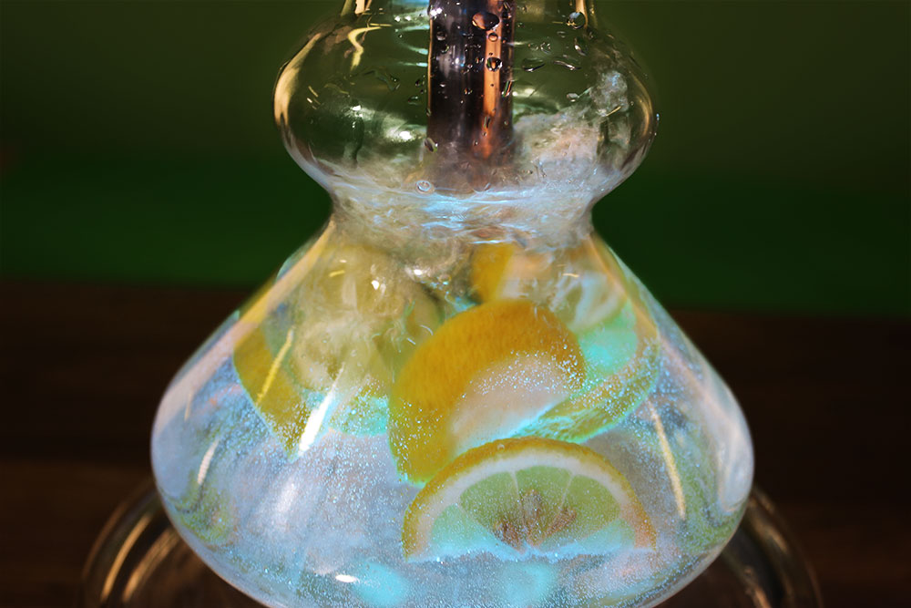 Zitronenspalten in einem Shishaglas. Von unten mit blauem Licht beleuchtet